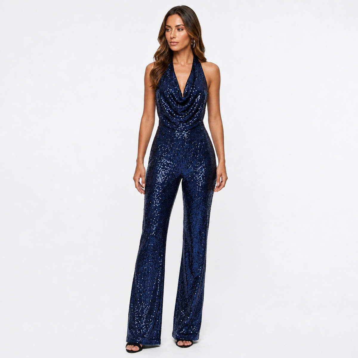 Brunette model in blauwe sequin halter jumpsuit op witte achtergrond